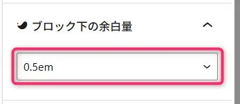 Webビルダーのブロック設定パネル。「ブロック下の余白量」セクションヘッダーの横に折りたたみ矢印アイコンが配置され、その下のピンク枠で囲まれたドロップダウンメニューに「0.5em」という余白値が選択表示されているスペーシング設定画面