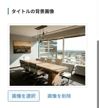 ページタイトル背景画像設定。モダンなオフィス環境の写真。大きな窓から都市景観が見える明るい空間、木製デスク、黒いオフィスチェア、天井のペンダントライト、壁掛けアート。「画像を選択」と「画像を削除」ボタンで背景画像管理